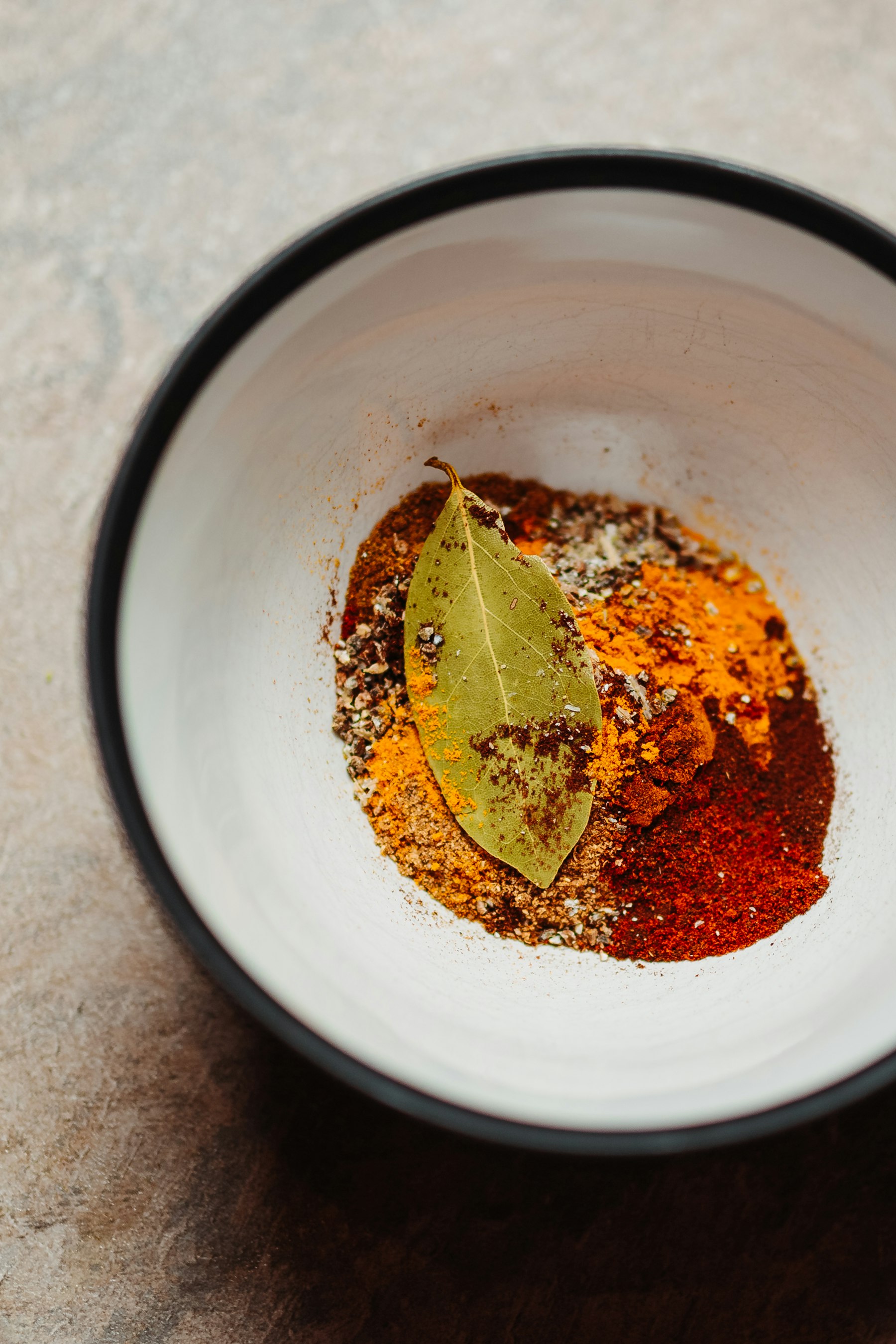 A bowl of carefully arranged spices on stone